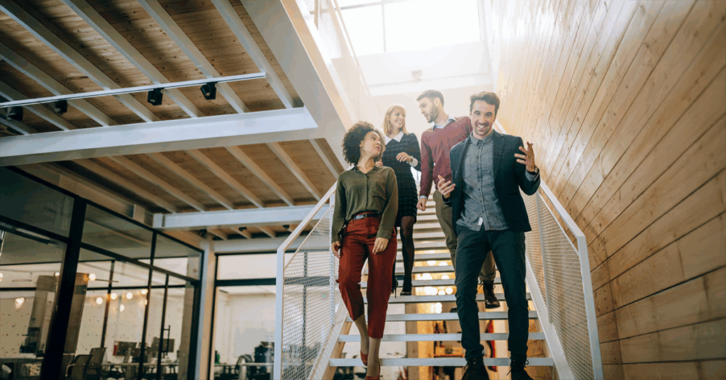 4 Personen gehen eine Treppe in einem Büro hinab. Sie wirken energiegeladen und motiviert. Symbolbild zum Thema Biohacking.