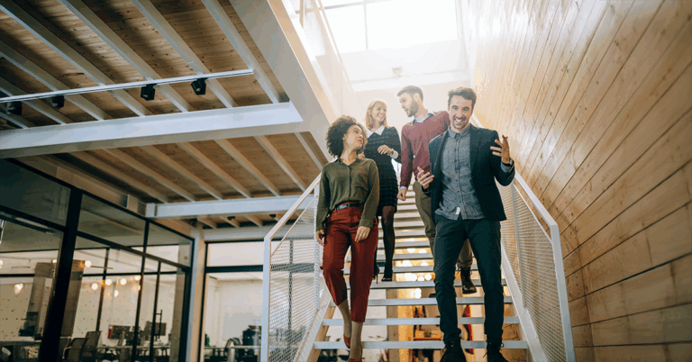 4 Personen gehen eine Treppe in einem Büro hinab. Sie wirken energiegeladen und motiviert. Symbolbild zum Thema Biohacking.