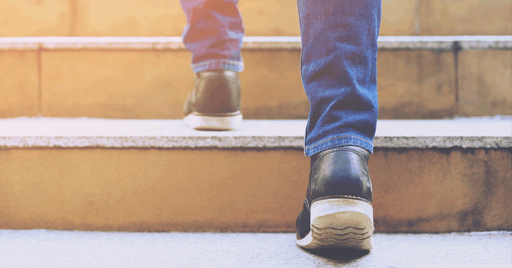Eine Person steigt Treppenstufen hinauf, Detailsaufnahme der Füße