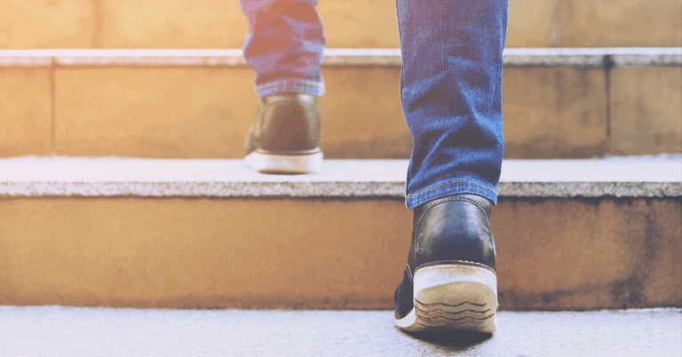 Eine Person steigt Treppenstufen hinauf, Detailsaufnahme der Füße