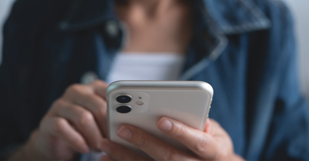 Nahaufnahme einer Frau, die ein Smartphone in den Händen hält